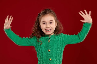 Kırmızı bir arka plan aleyhine poz uzun, kıvırcık saçlı küçük bir esmer kız Portresi.