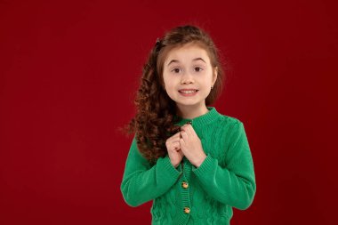 Kırmızı bir arka plan aleyhine poz uzun, kıvırcık saçlı küçük bir esmer kız Portresi.