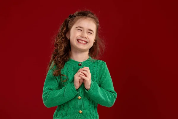 Retrato de una niña morena con el pelo largo y rizado posando sobre un fondo rojo . —  Fotos de Stock