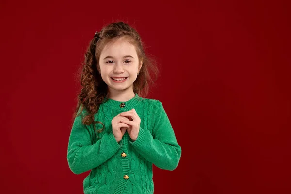 Retrato de una niña morena con el pelo largo y rizado posando sobre un fondo rojo . —  Fotos de Stock