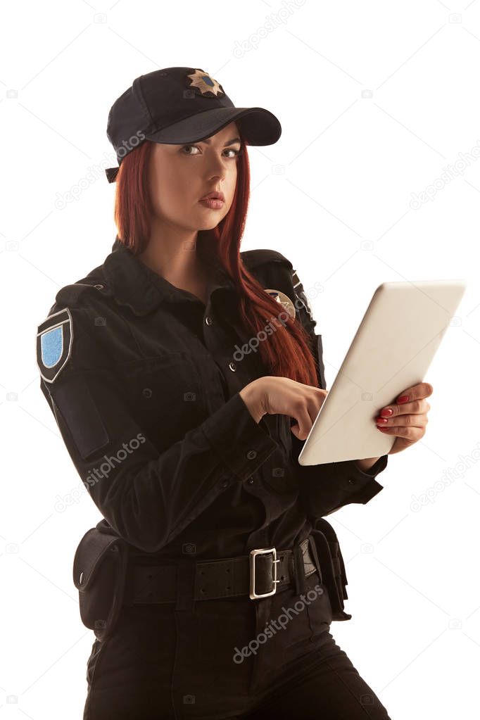 Redheaded female police officer is posing for the camera isolated on white background.
