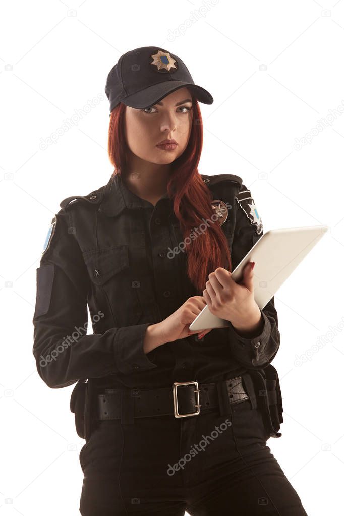 Redheaded female police officer is posing for the camera isolated on white background.