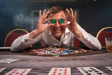 Yakışıklı duygusal adam kumarhanede masada poker oynuyor..