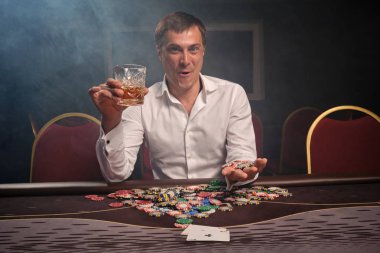 Yakışıklı duygusal adam kumarhanede masada poker oynuyor..