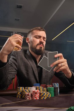 Yakışıklı sakallı adam kumarhanede masada poker oynuyor..