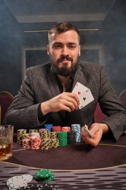 Yakışıklı sakallı adam kumarhanede masada poker oynuyor..