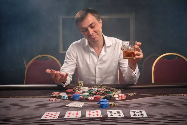 Schöner emotionaler Mann pokert am Tisch im Casino. — Stockfoto