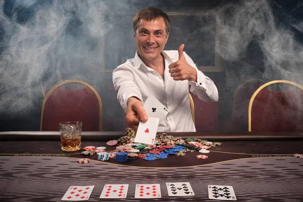 Bel homme émotionnel joue au poker assis à la table dans le casino . — Photo