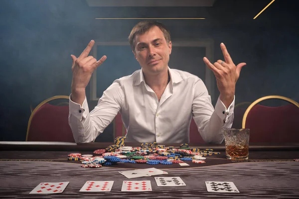 Schöner emotionaler Mann pokert am Tisch im Casino. — Stockfoto