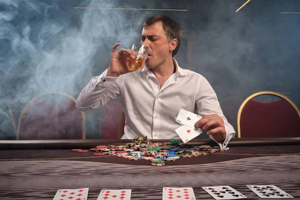 Schöner emotionaler Mann pokert am Tisch im Casino. — Stockfoto