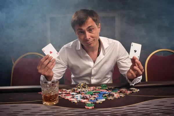 Snygg känslomässig man spelar poker sitter vid bordet i kasino. — Stockfoto