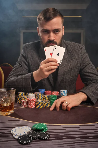 Hombre barbudo guapo está jugando póquer sentado en la mesa en el casino . —  Fotos de Stock