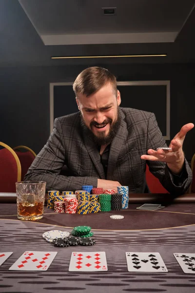 Snygg skäggig man spelar poker sitter vid bordet i kasino. — Stockfoto