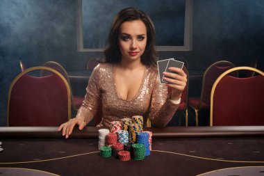 Güzel esmer kadın kumarhanede masada poker oynuyor..