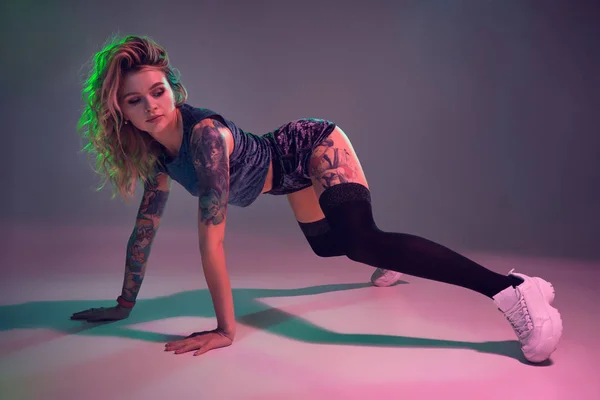 Vacker kaukasiska blond flicka i velour blå Booty shorts och svarta strumpor dansar twerk på rosa bakgrund — Stockfoto