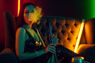Seksi esmer model lüks bir gece kulübünde bir duman nefes bir nargile içiyor.