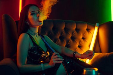 Seksi esmer model lüks bir gece kulübünde bir duman nefes bir nargile içiyor.