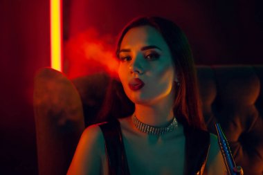Seksi esmer model lüks bir gece kulübünde bir duman nefes bir nargile içiyor.