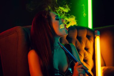 Seksi esmer model lüks bir gece kulübünde bir duman nefes bir nargile içiyor.