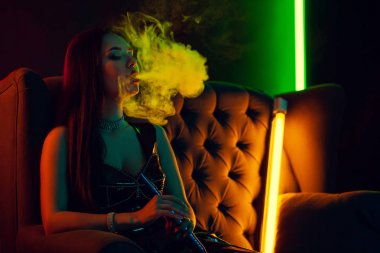 Seksi esmer model lüks bir gece kulübünde bir duman nefes bir nargile içiyor.