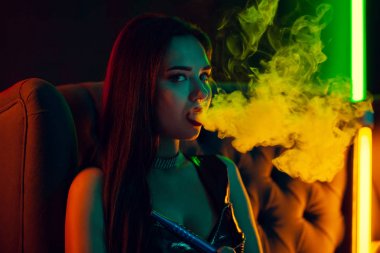 Seksi esmer model lüks bir gece kulübünde bir duman nefes bir nargile içiyor.