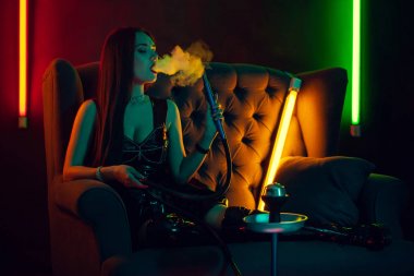 Seksi esmer model lüks bir gece kulübünde bir duman nefes bir nargile içiyor.