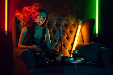 Seksi esmer model lüks bir gece kulübünde bir duman nefes bir nargile içiyor.
