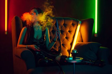 Seksi esmer model lüks bir gece kulübünde bir duman nefes bir nargile içiyor.