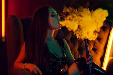 Seksi esmer model lüks bir gece kulübünde bir duman nefes bir nargile içiyor.