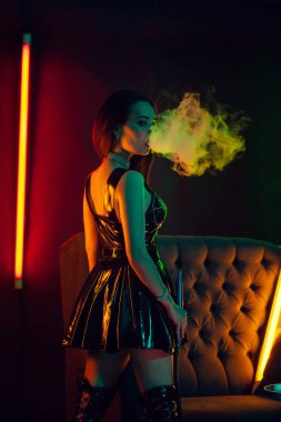Seksi esmer model lüks bir gece kulübünde bir duman nefes bir nargile içiyor.