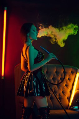 Seksi esmer model lüks bir gece kulübünde bir duman nefes bir nargile içiyor.