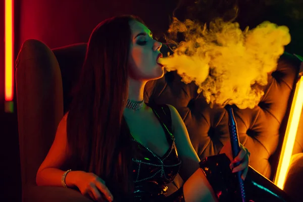 Sexy brünettes Model raucht in einem luxuriösen Nachtclub eine Wasserpfeife. — Stockfoto