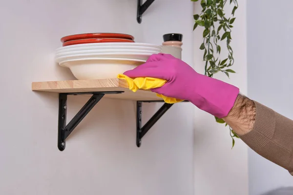 Young handsome strong hands in pink gloves cleans the shelf above the cooking surface using detergents, close up view — Stock Photo, Image