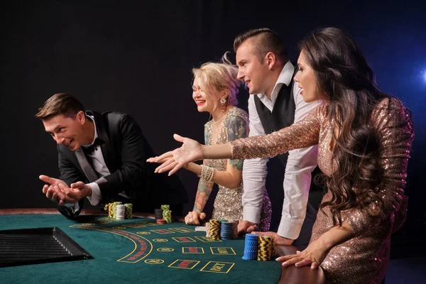 Ομάδα από ένα κομψό πλούσιους φίλους παίζουν πόκερ στο καζίνο. — Φωτογραφία Αρχείου