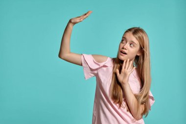 Mavi bir arka plan üzerinde poz pembe bir t-shirt güzel bir kız sarışın genç Stüdyo portresi.