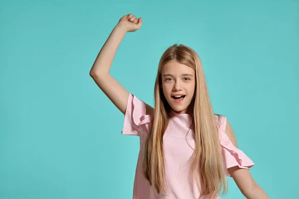 푸른 배경 위에 포즈를 취하는 분홍색 티셔츠를 입은 아름다운 소녀 금발의 십대의 스튜디오 초상화. — 스톡 사진