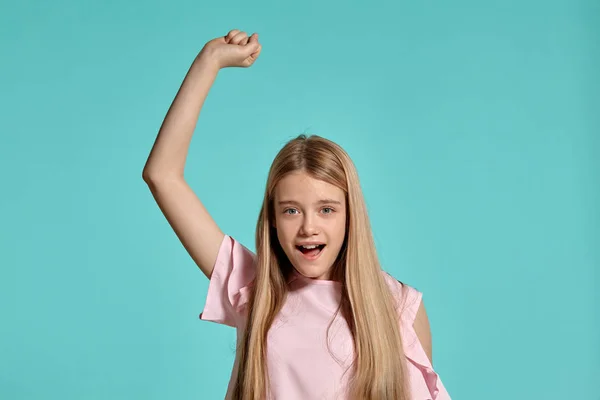 Studio portret van een mooi meisje blonde tiener in een roze t-shirt poseren over een blauwe achtergrond. — Stockfoto