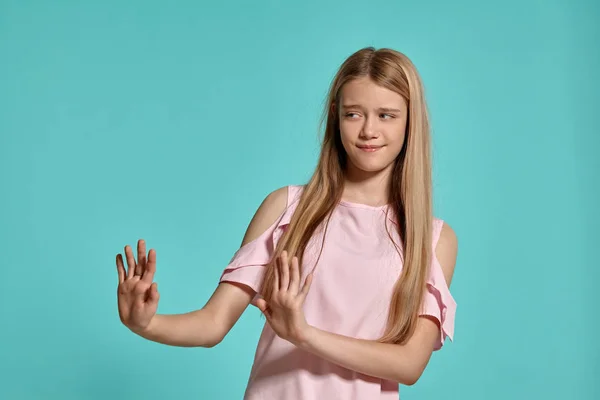 Estúdio retrato de uma bela menina adolescente loira em uma camiseta rosa posando sobre um fundo azul . — Fotografia de Stock