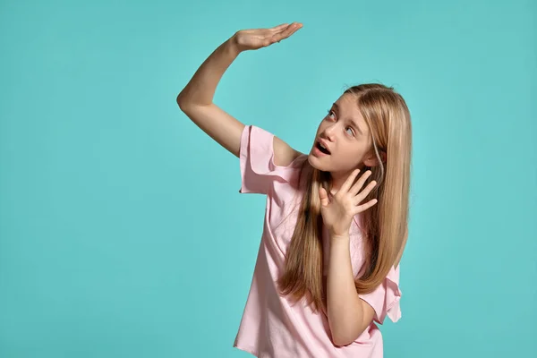 Estúdio retrato de uma bela menina adolescente loira em uma camiseta rosa posando sobre um fundo azul . — Fotografia de Stock