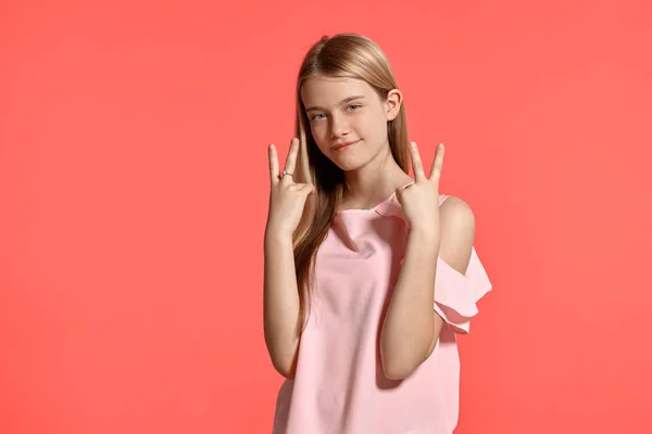 Estúdio retrato de uma bela menina adolescente loira em uma camiseta rosada posando no fundo rosa . — Fotografia de Stock