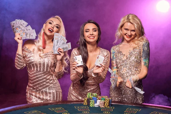 Schöne Mädchen mit perfekten Frisuren und hellem Make-up posieren an einem Spieltisch. Casino, Poker. — Stockfoto