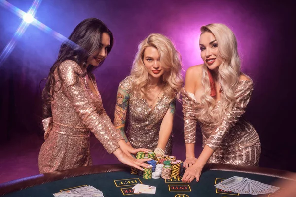 Meninas bonitas com penteados perfeitos e maquiagem brilhante estão posando em pé em uma mesa de jogo. Casino, poker . — Fotografia de Stock