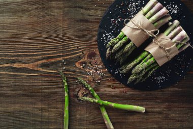 Ahşap bir arka plan üzerinde kuşkonmaz yenilebilir, ham sapları.