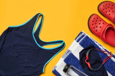 Sarı bir arka plan üzerinde düz yatıyordu yaz havuzu aksesuarları. Renkli plaj giyimi.