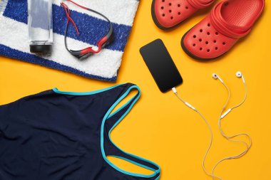 Sarı bir arka plan üzerinde düz yatıyordu yaz havuzu aksesuarları. Renkli plaj giyimi.