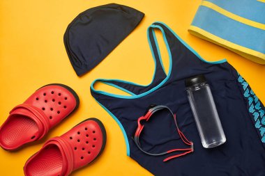 Sarı bir arka plan üzerinde düz yatıyordu yaz havuzu aksesuarları. Renkli plaj giyimi.