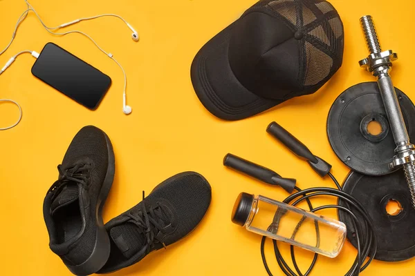 Close-up studio shot of a gym accessories on a yellow background. Top view, flat lay.