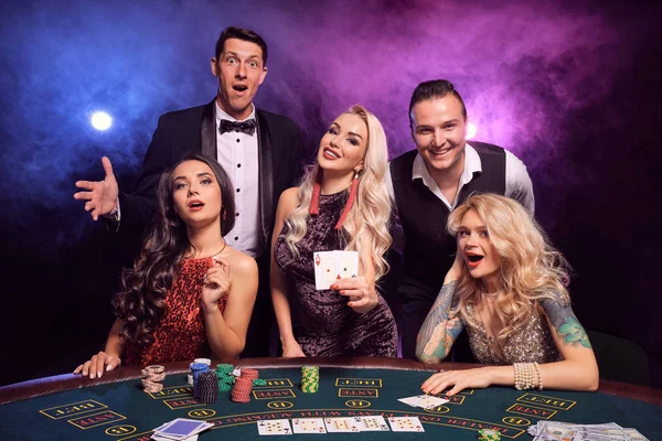 Groep van een jonge rijke vrienden spelen poker in een casino. — Stockfoto