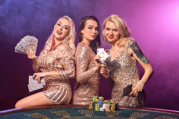 Meninas bonitas com penteados perfeitos e maquiagem brilhante estão posando em pé em uma mesa de jogo. Casino, poker . — Fotografia de Stock