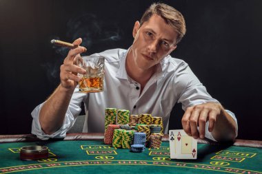 Yakışıklı duygusal adam kumarhanede beyaz spot ışıklarına karşı poker oynuyor..